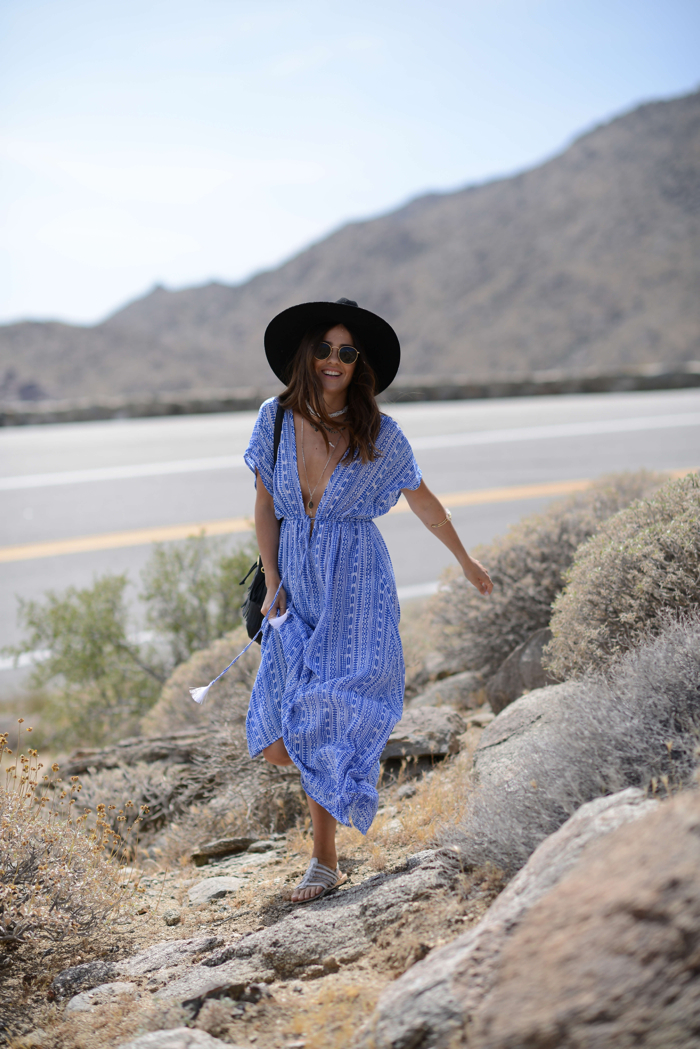 a girl smiling as she steps on rocks in a maxi dress and a hat