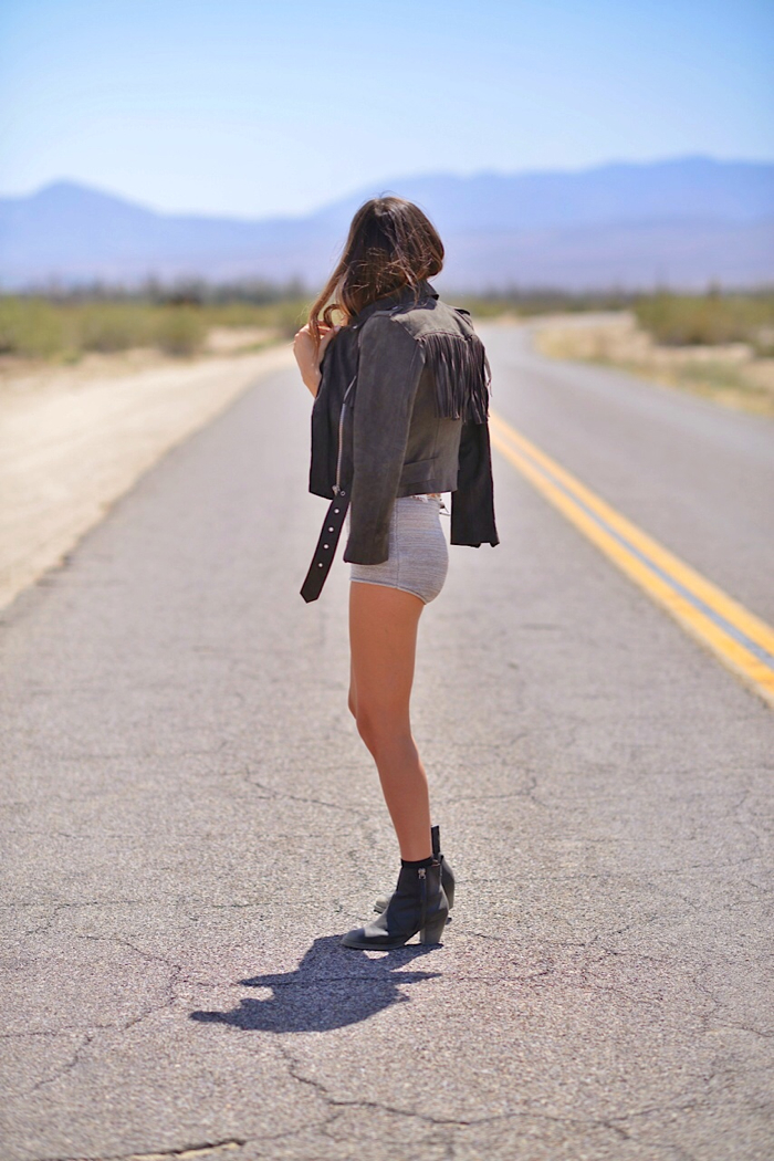 Paola Alberdi looking down the road touching my hair wearing amuse society shorts with acne booties