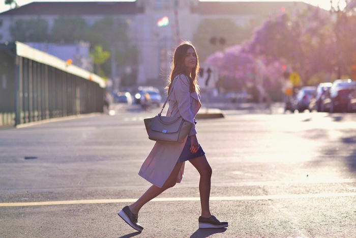 Paola Alberdi looking towards the camera crossing the street with the sunset light behind her. 