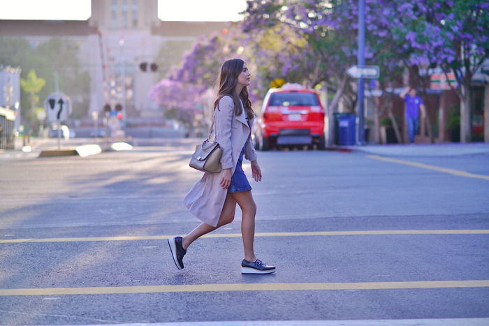 crossing the street wearing trench coat and denim skirt