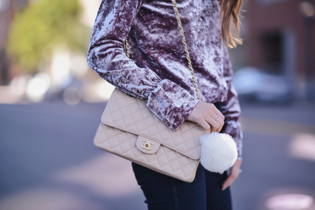 Chanel handbag with white pompom accessory.