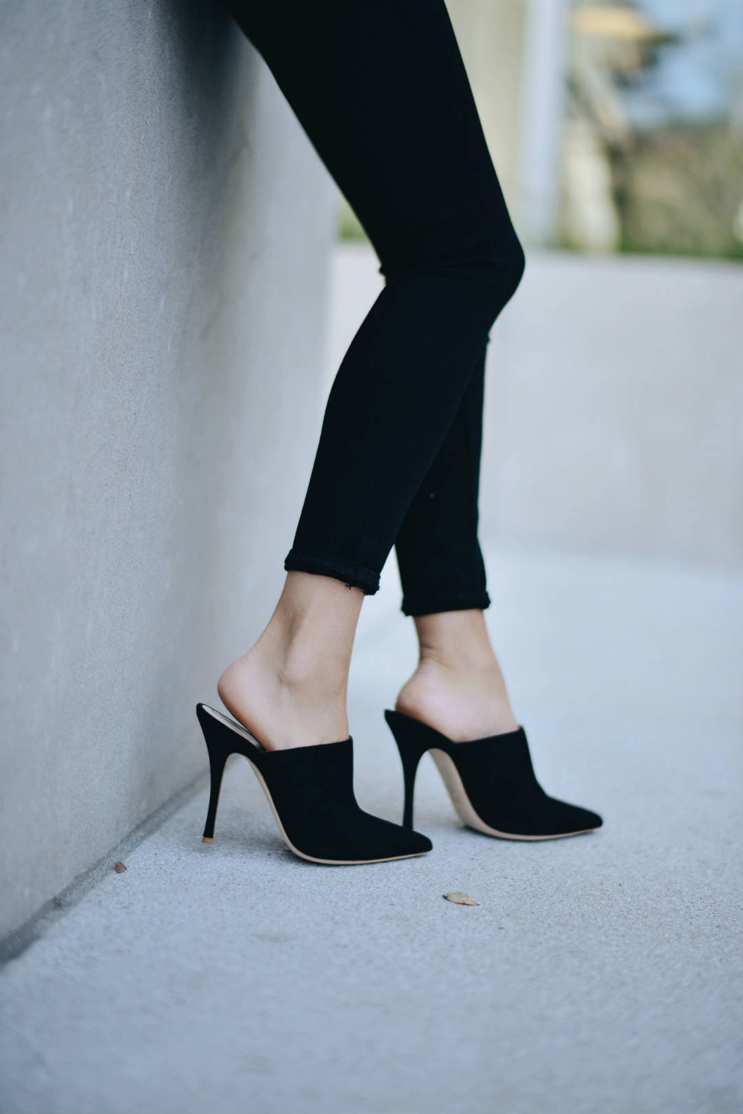 Close-up detailed shot of stiletto black suede mule heels.