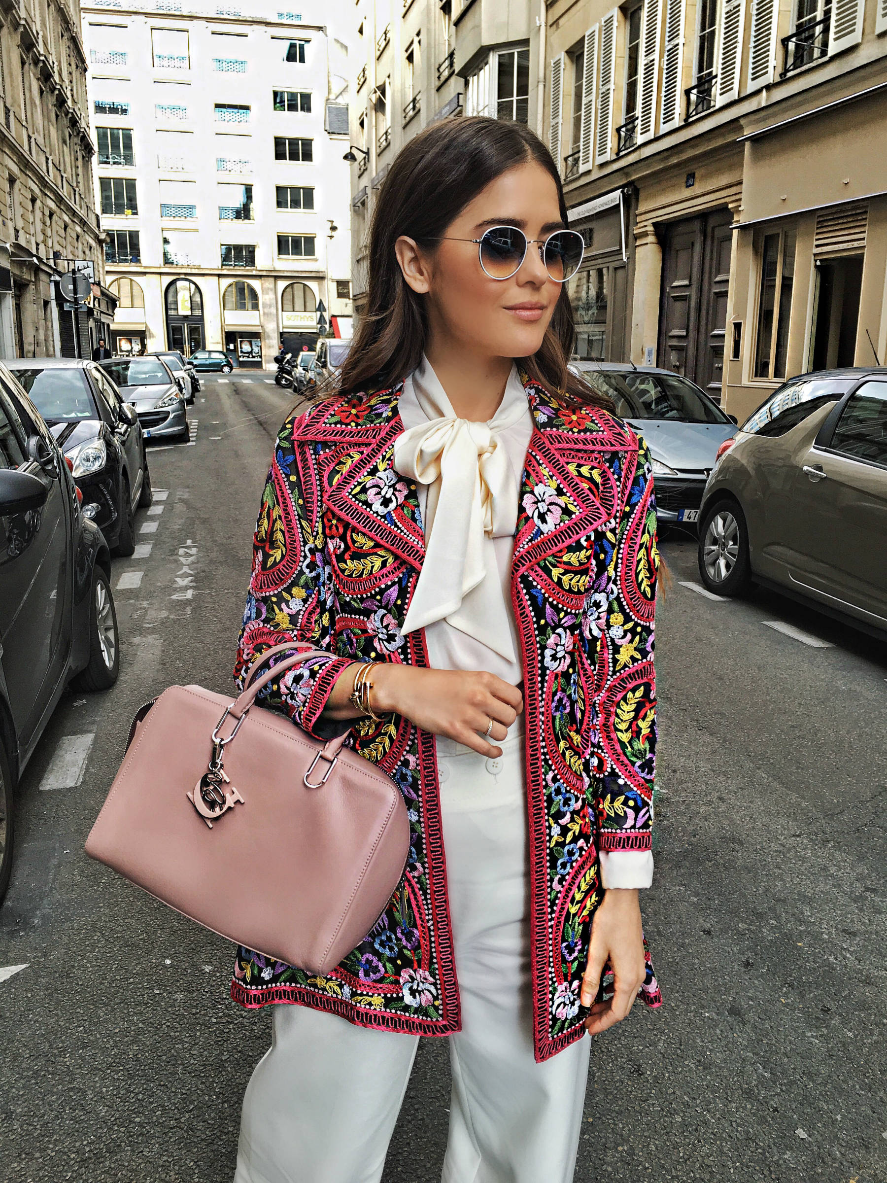 Paola Alberdi in a colorful embroidered jacket in a Parisian street.